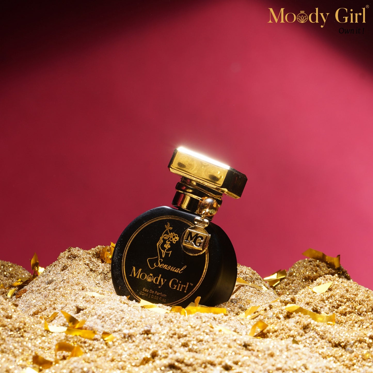 Moody Girl Sensual 20ml Perfume bottle labeled 'Moody Girl' on a sand-like surface with a pink background